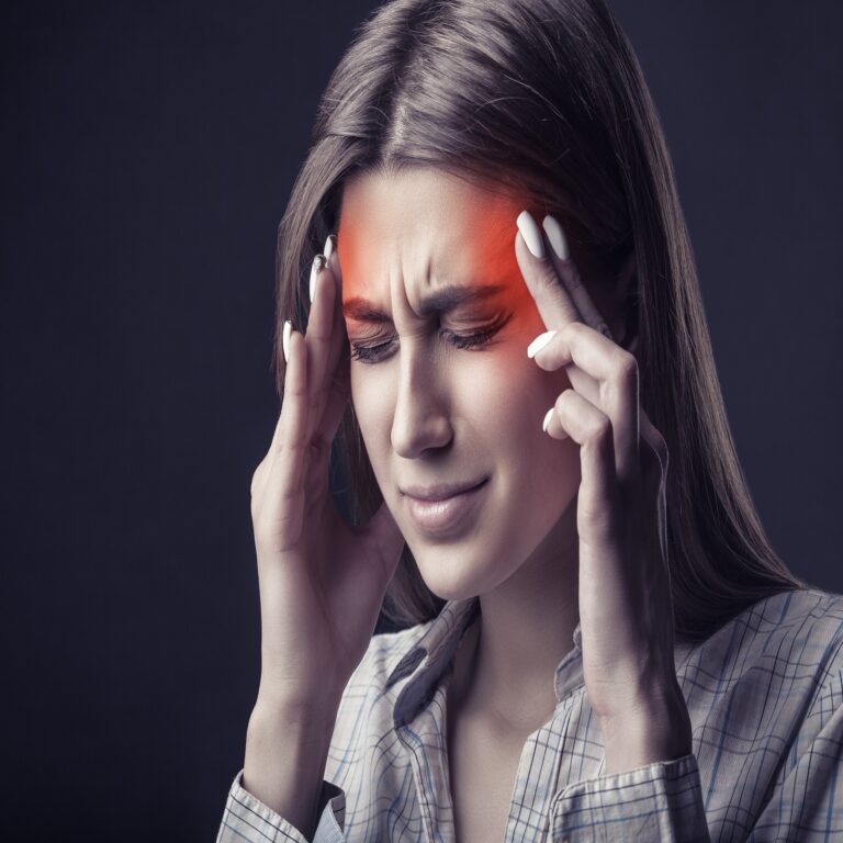 Young,Woman,Is,Suffering,From,A,Headache,Against,A,Dark